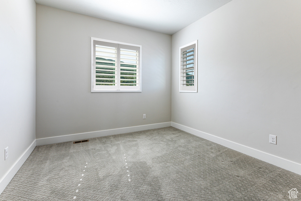 Carpeted empty room with healthy amount of natural light and baseboards