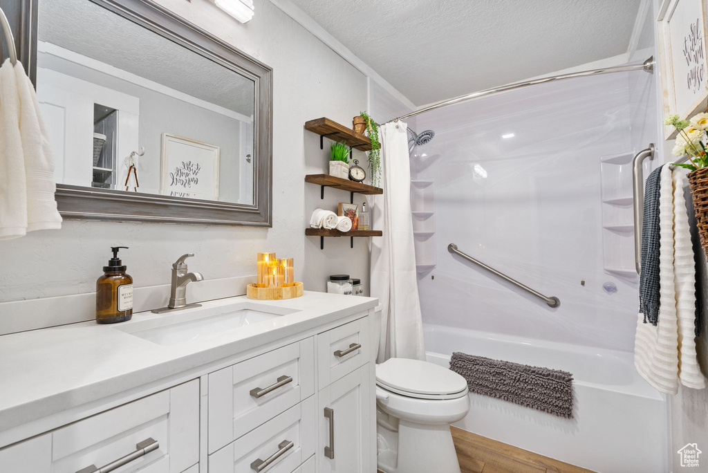 Bathroom featuring shower / bath combination with curtain, vanity, toilet, wood finished floors, and a textured ceiling