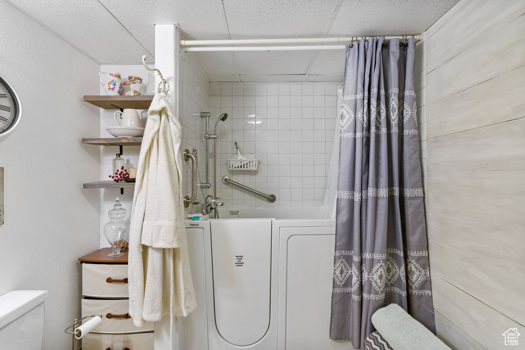 Bathroom featuring toilet, shower / tub combo, and washer / clothes dryer