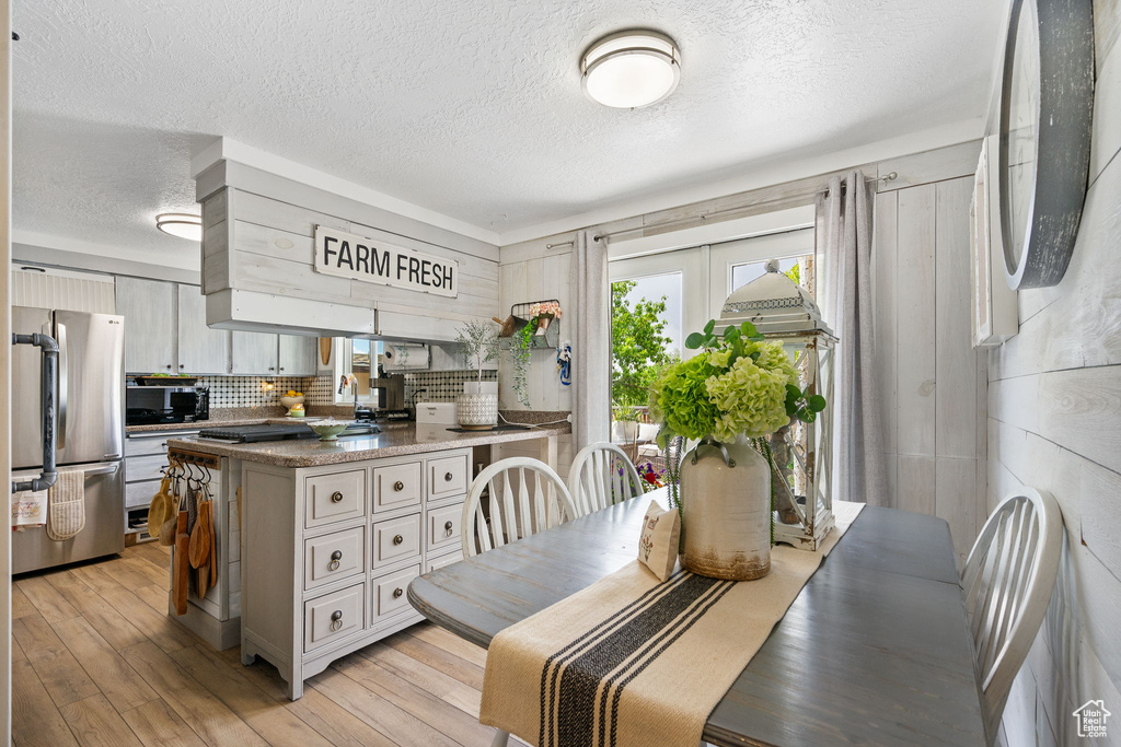 Dining area with a textured ceiling, healthy amount of natural light, and light wood-style flooring