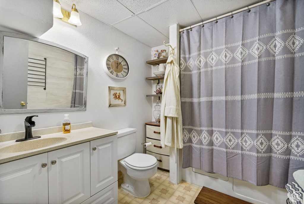 Bathroom with toilet, vanity, a paneled ceiling, tile patterned floors, and shower / bath combo