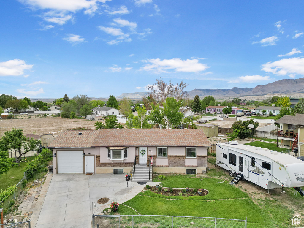 Ranch-style house featuring a mountain view, concrete driveway, a residential view, and roof with shingles