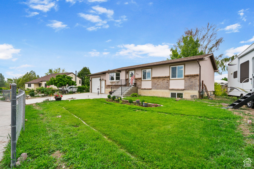 View of front of property with a garage, brick siding, driveway, and stucco siding