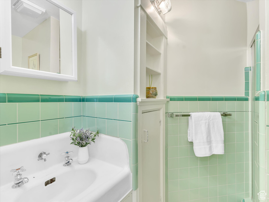 Full bathroom with tile walls, a sink, and wainscoting