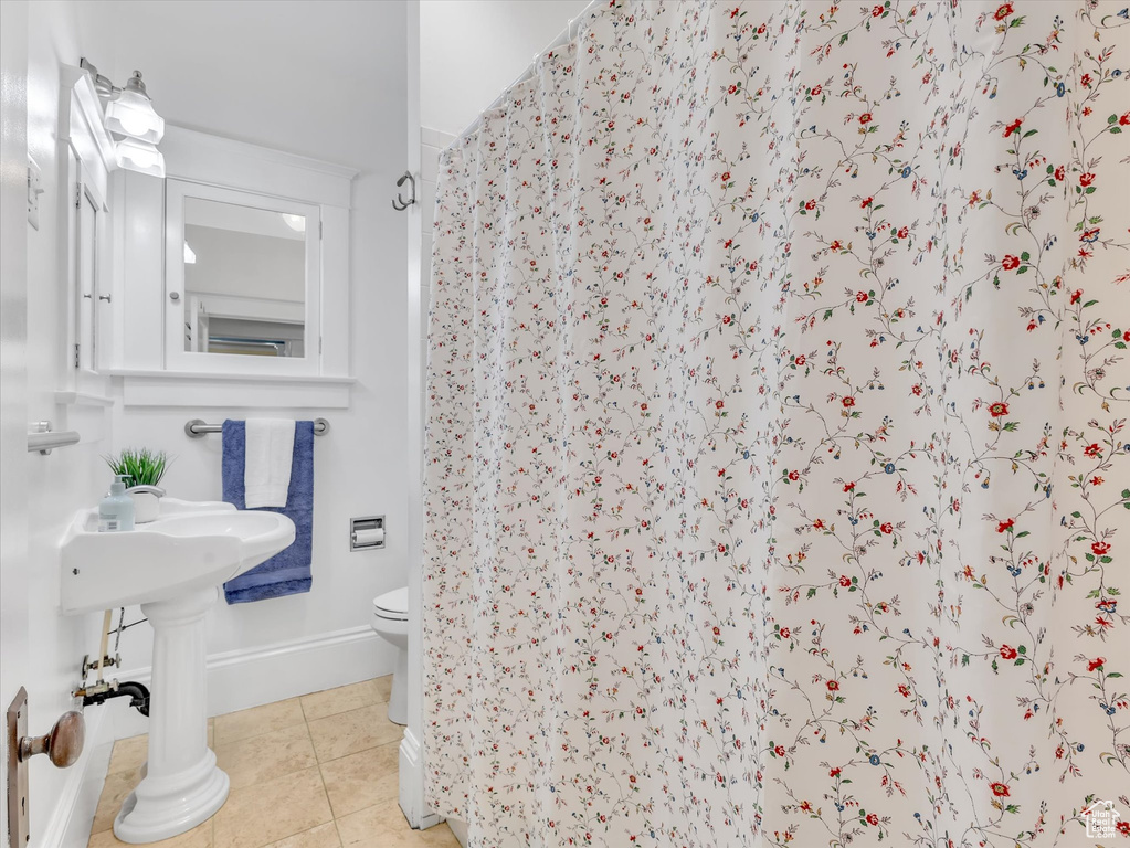 Full bathroom featuring toilet, a shower with curtain, tile patterned floors, and baseboards