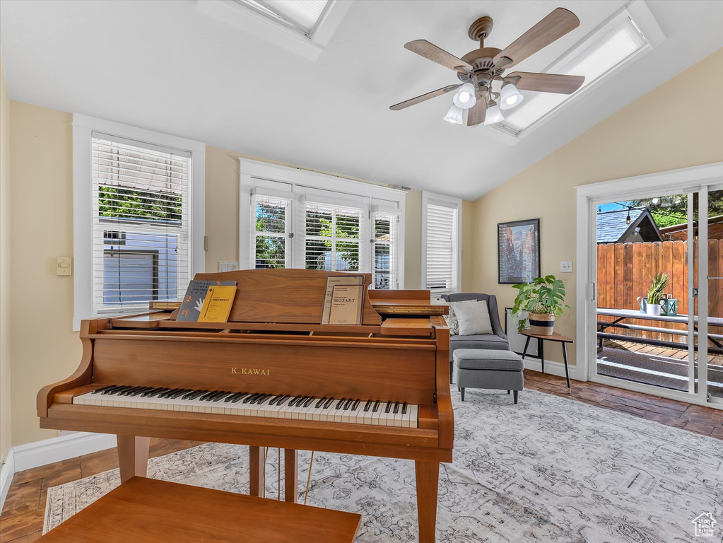 Living area with lofted ceiling, baseboards, and a ceiling fan