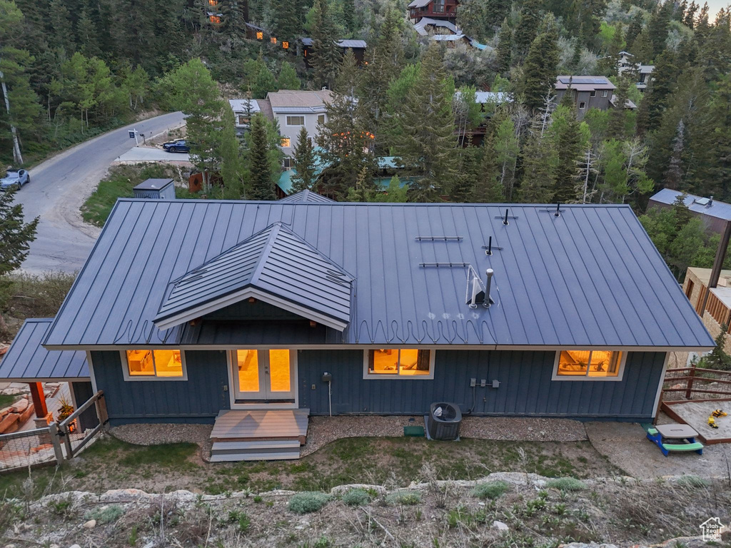 View of front of home with a standing seam roof, metal roof, and a wooded view