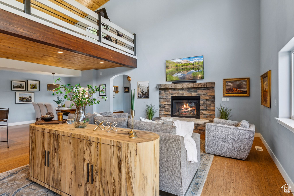 Living area with a high ceiling, wood finished floors, arched walkways, baseboards, and recessed lighting