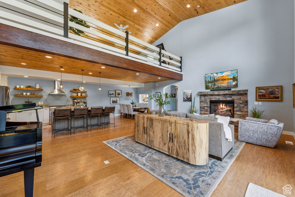 Living area featuring wooden ceiling, light wood-style floors, a stone fireplace, recessed lighting, and high vaulted ceiling