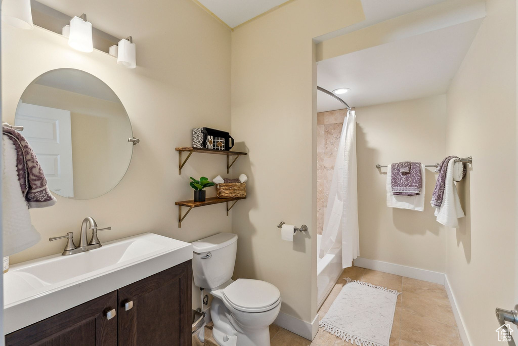 Bathroom featuring vanity, toilet, baseboards, shower / tub combo, and tile patterned floors