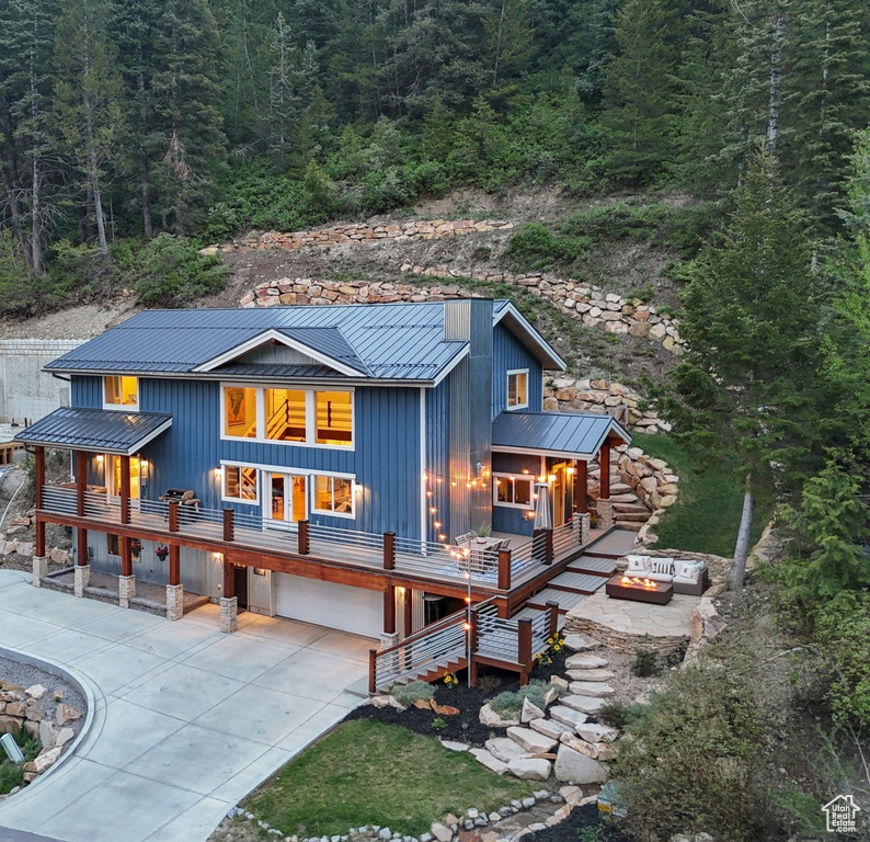 View of front facade featuring a standing seam roof, metal roof, board and batten siding, and an outdoor fire pit