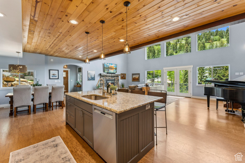 Kitchen with stainless steel dishwasher, a sink, arched walkways, open floor plan, and light stone counters