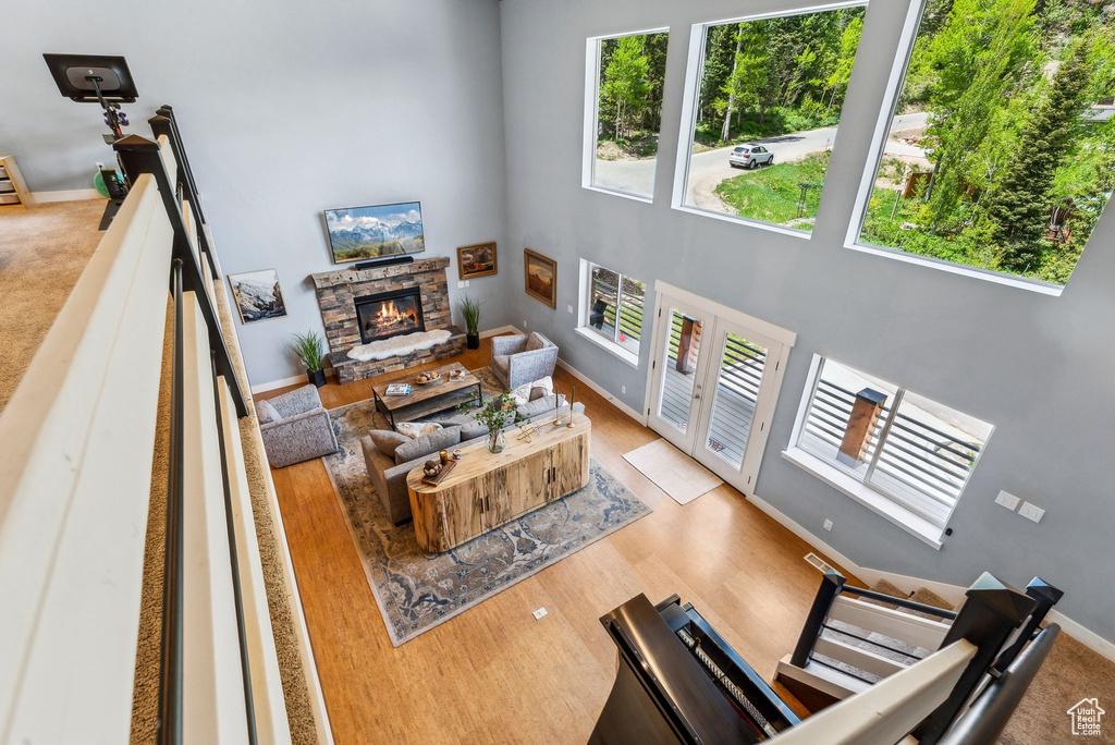 Living room featuring a stone fireplace, a towering ceiling, baseboards, and wood finished floors