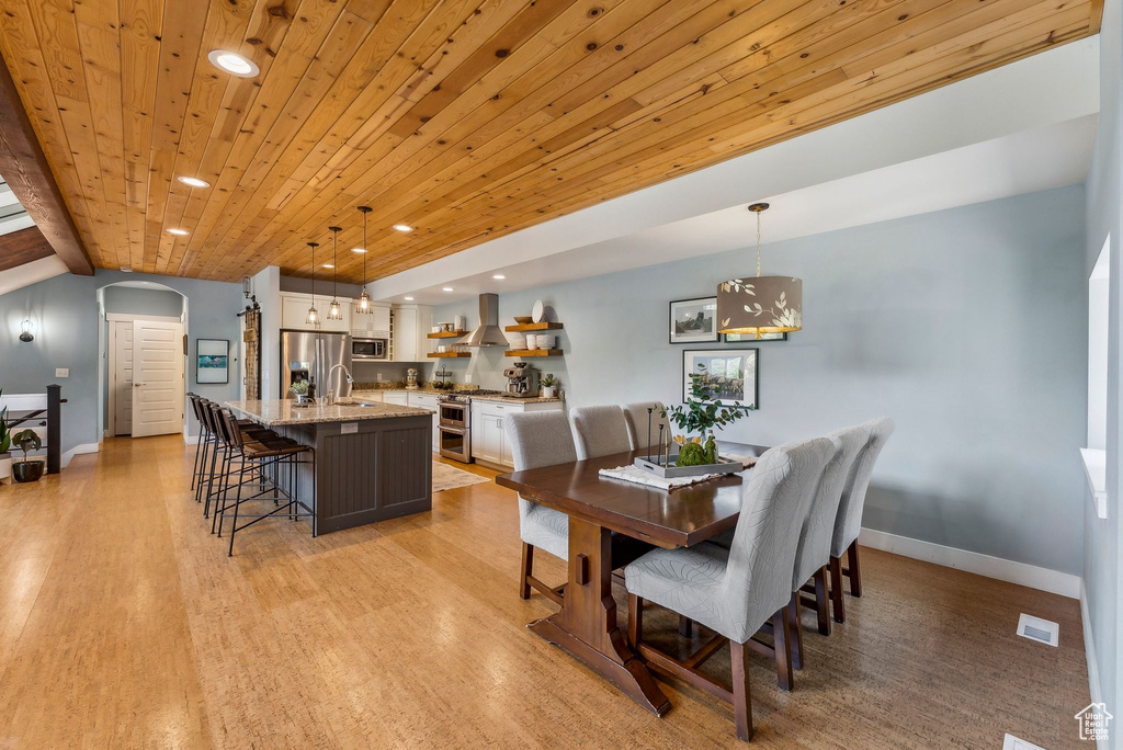 Dining room featuring arched walkways, baseboards, recessed lighting, wood ceiling, and light wood-style flooring