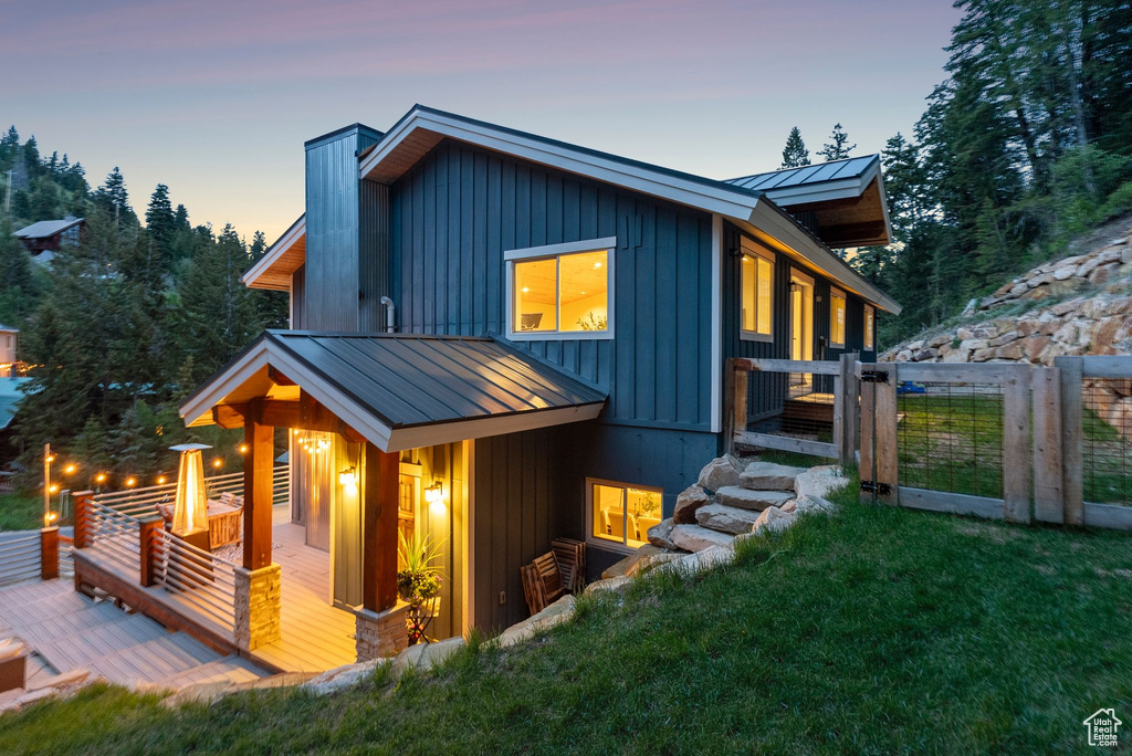 View of front of property with a standing seam roof, a deck, a front lawn, a chimney, and metal roof