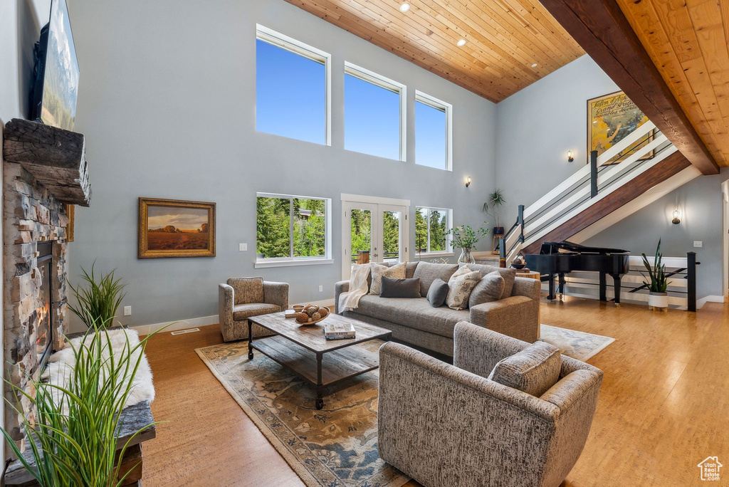Living room with wood ceiling, stairway, wood finished floors, a towering ceiling, and french doors