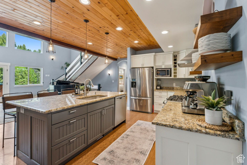 Kitchen with appliances with stainless steel finishes, a sink, open shelves, wooden ceiling, and white cabinetry