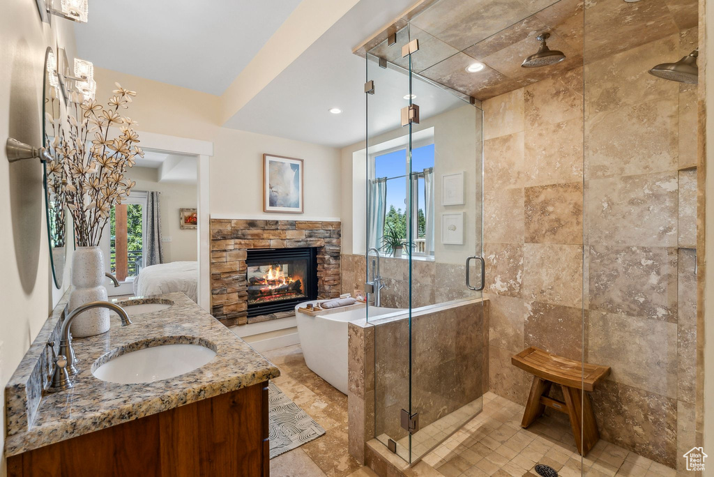 Full bathroom featuring double vanity, a stall shower, a freestanding tub, a fireplace, and recessed lighting