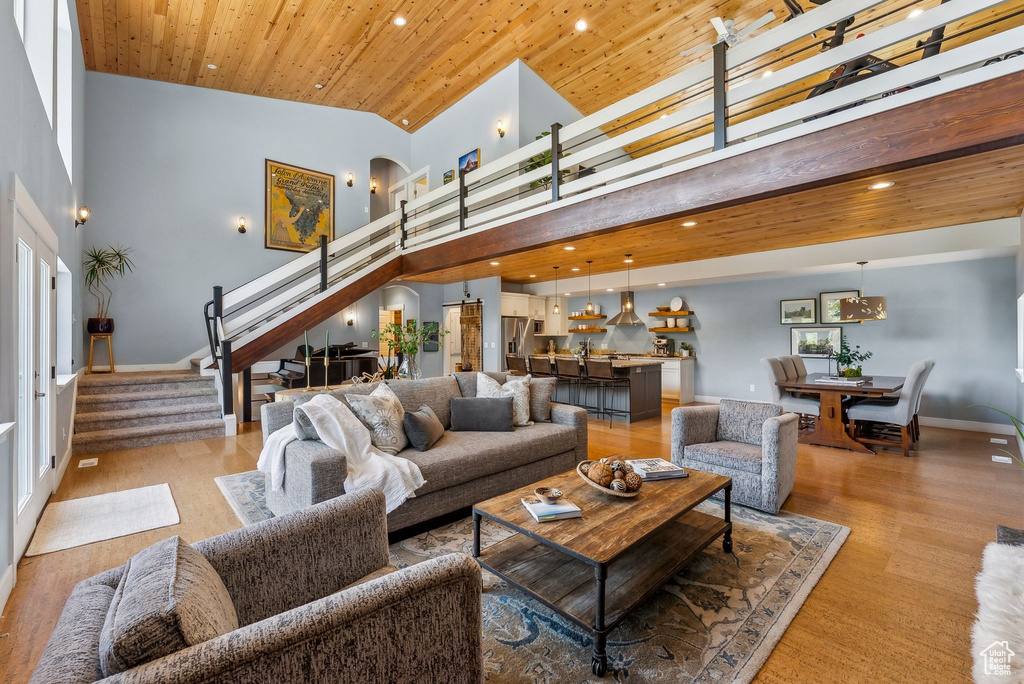 Living room with stairway, a towering ceiling, light wood-style flooring, recessed lighting, and arched walkways