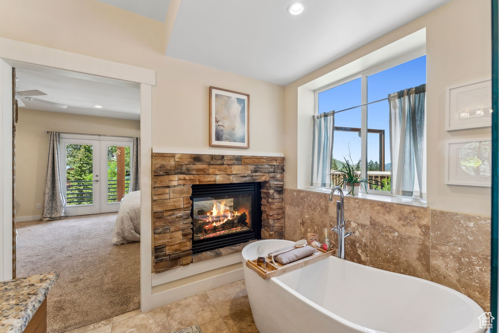 Full bathroom with a stone fireplace, a freestanding tub, recessed lighting, and french doors