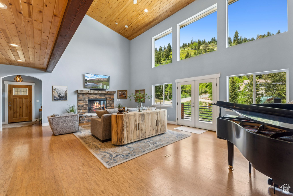 Living room with wood ceiling, wood finished floors, high vaulted ceiling, recessed lighting, and a stone fireplace