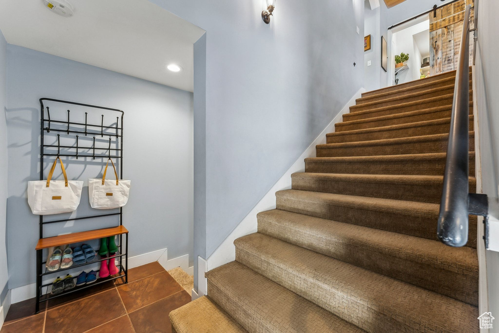 Stairs featuring baseboards, a barn door, recessed lighting, and tile patterned flooring