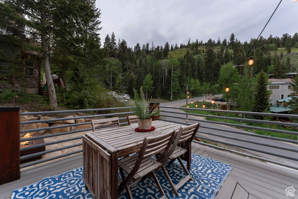 Wooden deck with a view of trees and outdoor dining space