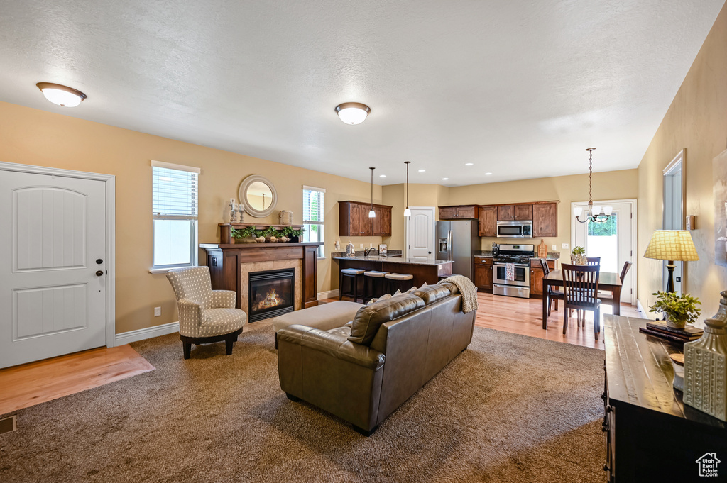 Carpeted living room featuring healthy amount of natural light, a tile fireplace, baseboards, and a chandelier