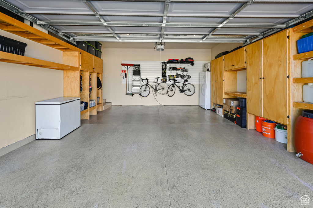 Garage with white fridge, a garage door opener, and washer / dryer