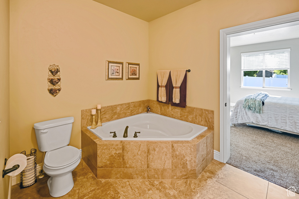 Full bathroom with toilet, a garden tub, ensuite bathroom, and tile patterned floors