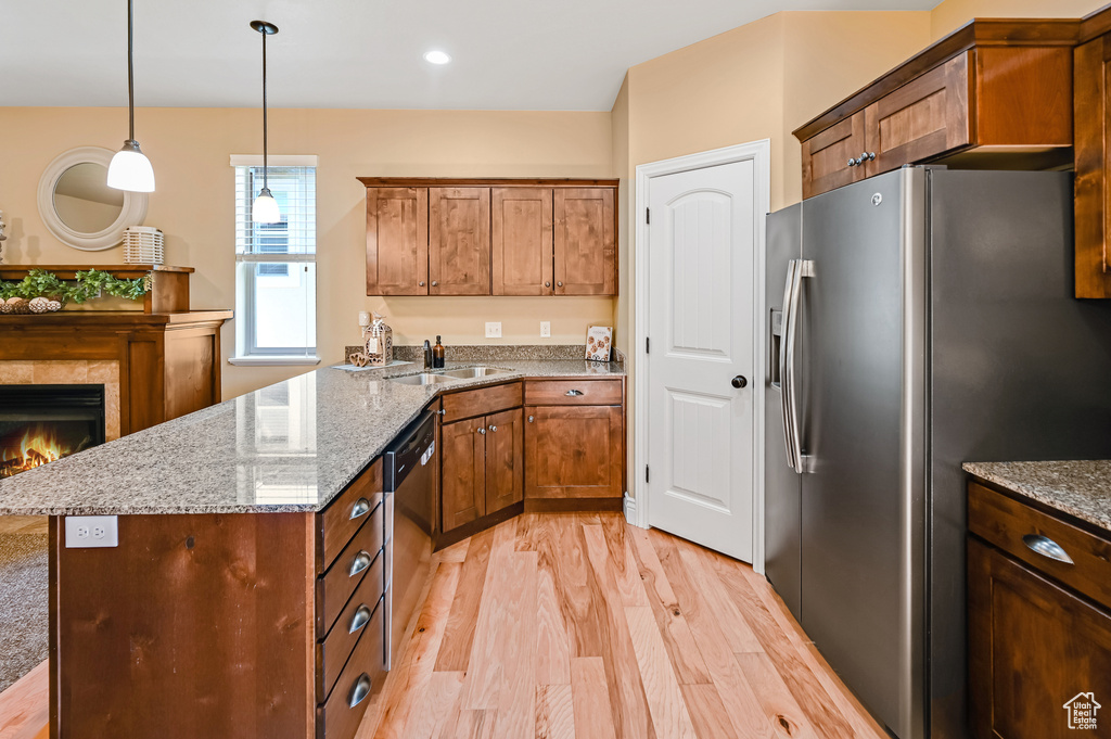 Kitchen with stainless steel appliances, a sink, light wood-style flooring, a peninsula, and hanging light fixtures