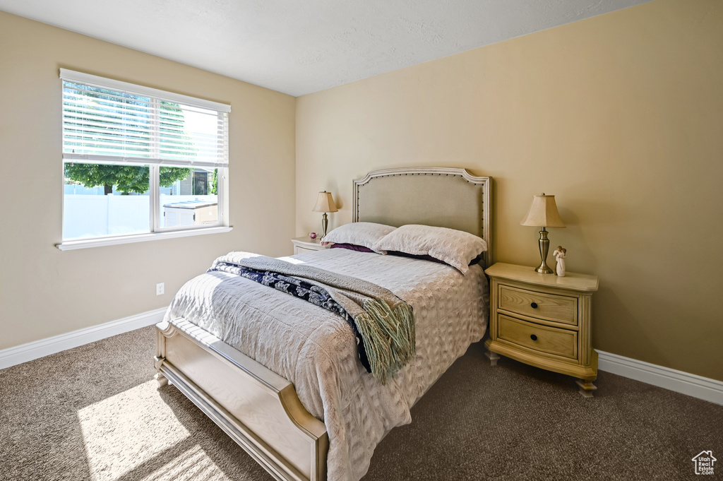 Bedroom featuring dark colored carpet and baseboards