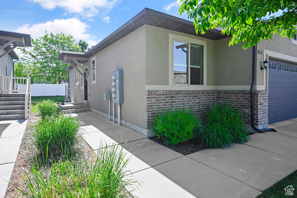 View of property exterior featuring stucco siding, brick siding, and a garage