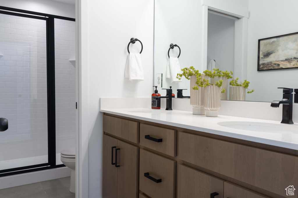Bathroom with toilet, double vanity, a stall shower, and tile patterned floors