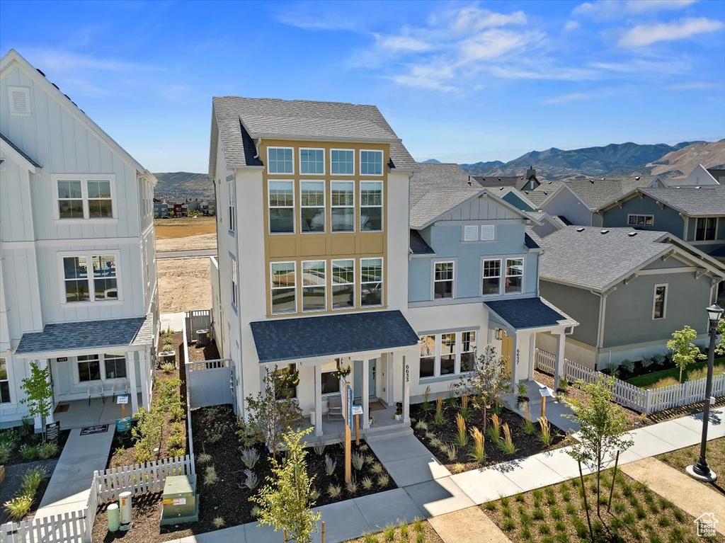 View of front of house featuring board and batten siding, a mountain view, roof with shingles, a residential view, and stucco siding