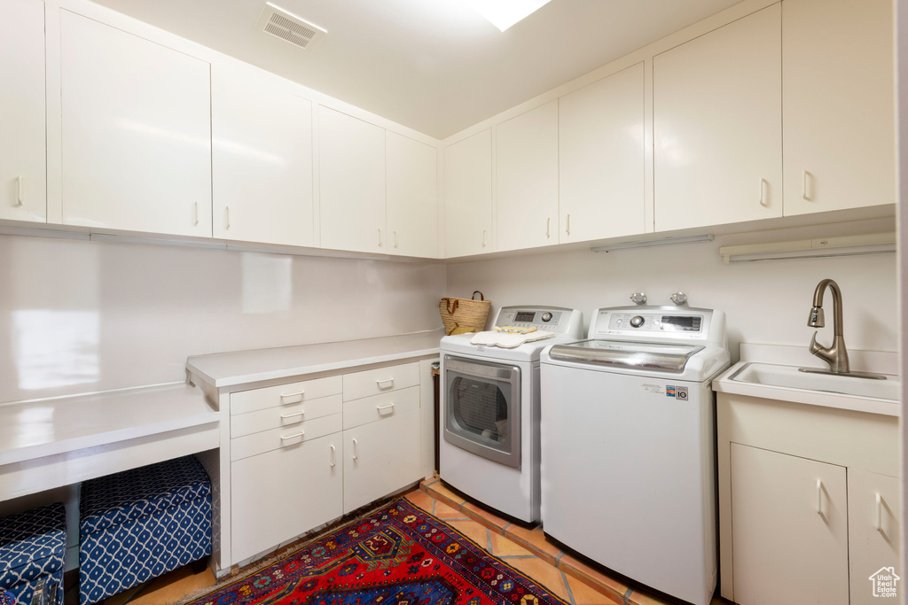 Laundry room with washing machine and clothes dryer, cabinet space, and light tile patterned floors