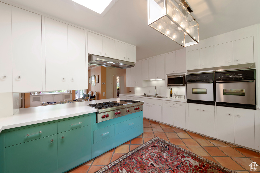 Kitchen with stainless steel appliances, a sink, light tile patterned flooring, and white cabinets