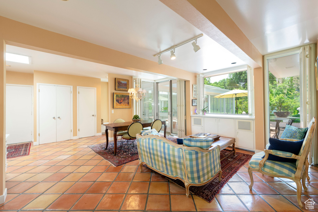Living room featuring track lighting, light tile patterned flooring, and a chandelier