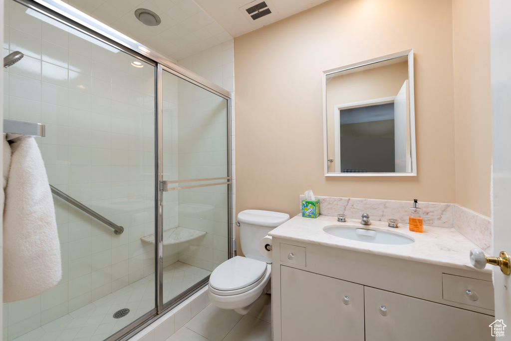 Bathroom featuring vanity, toilet, and a shower stall