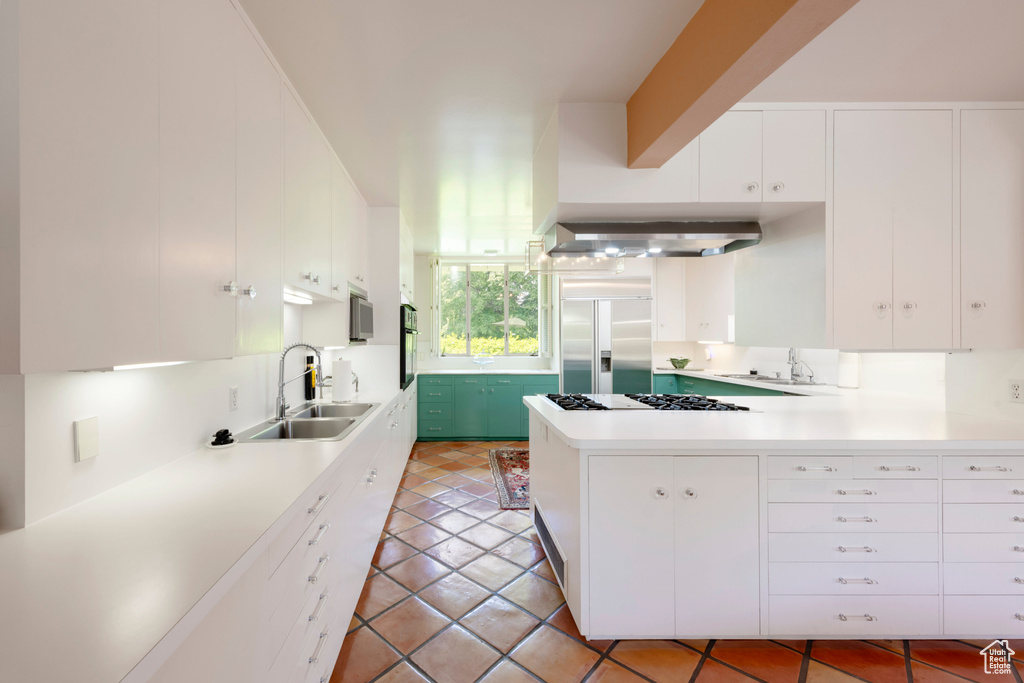 Kitchen with built in fridge, a sink, a peninsula, and light countertops