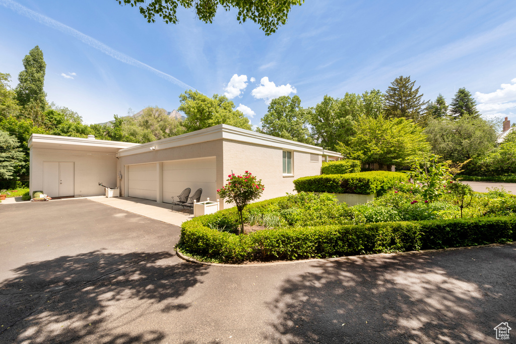 View of property exterior with asphalt driveway, an attached garage, and stucco siding