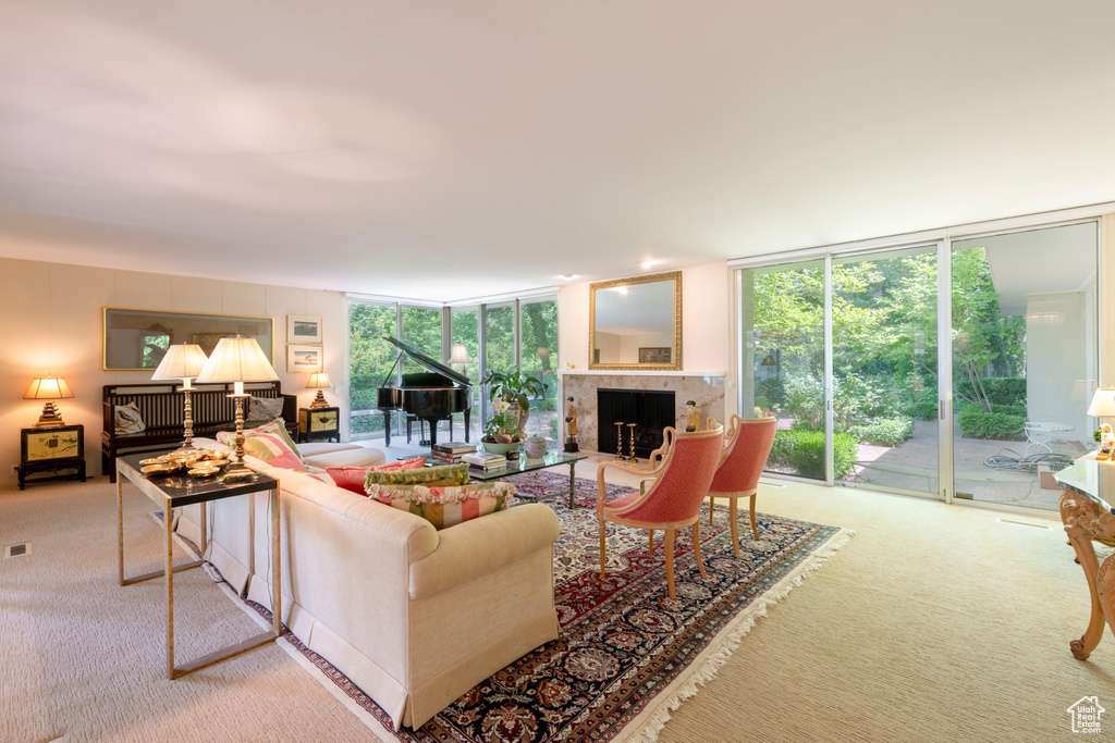 Carpeted living room with floor to ceiling windows, a tiled fireplace, and healthy amount of natural light
