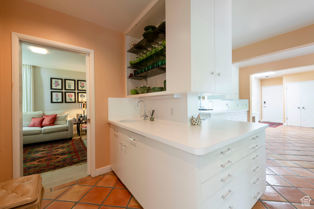 Kitchen with a sink, open shelves, light tile patterned floors, light countertops, and white cabinets
