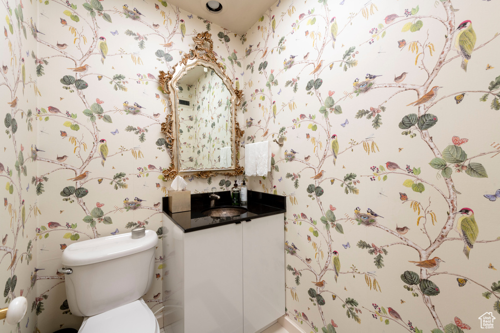 Bathroom with wallpapered walls, toilet, and vanity