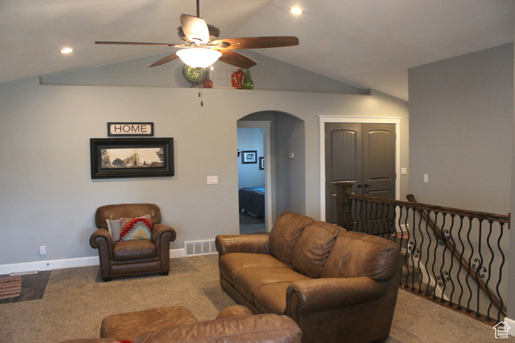 Carpeted living room featuring arched walkways, ceiling fan, vaulted ceiling, baseboards, and recessed lighting