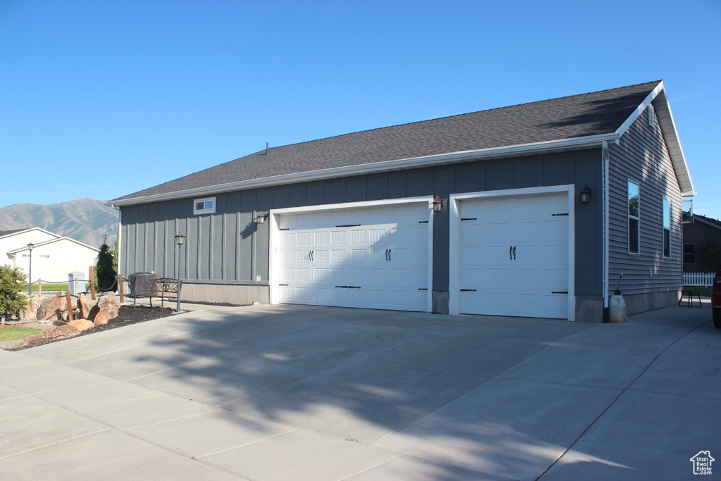 View of front of property with board and batten siding, a garage, a mountain view, a shingled roof, and driveway