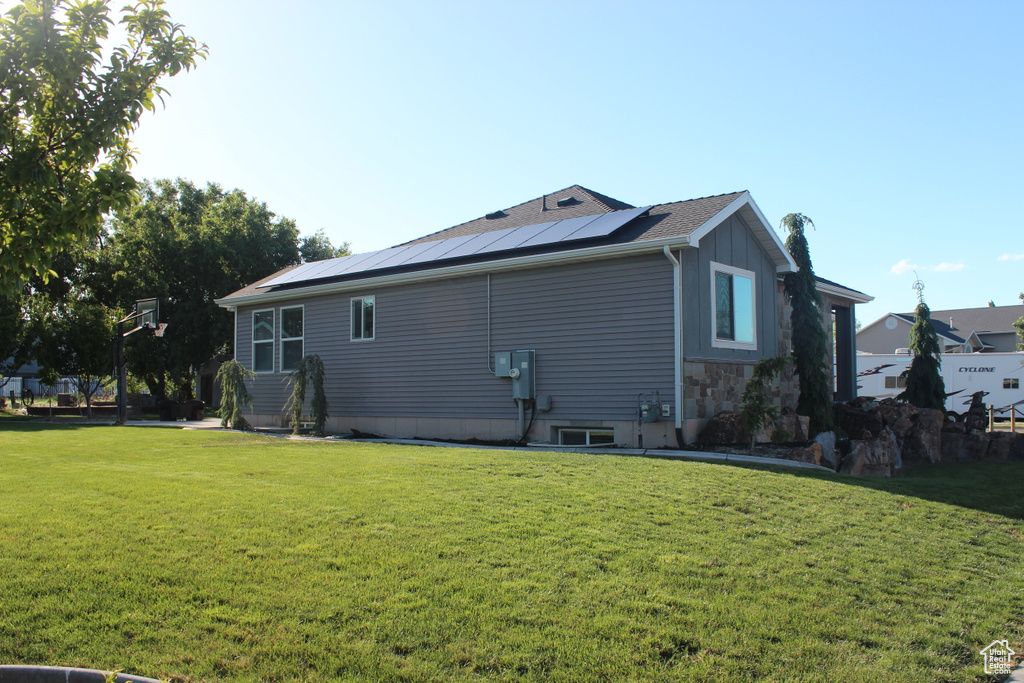View of side of home featuring a lawn, solar panels, and board and batten siding