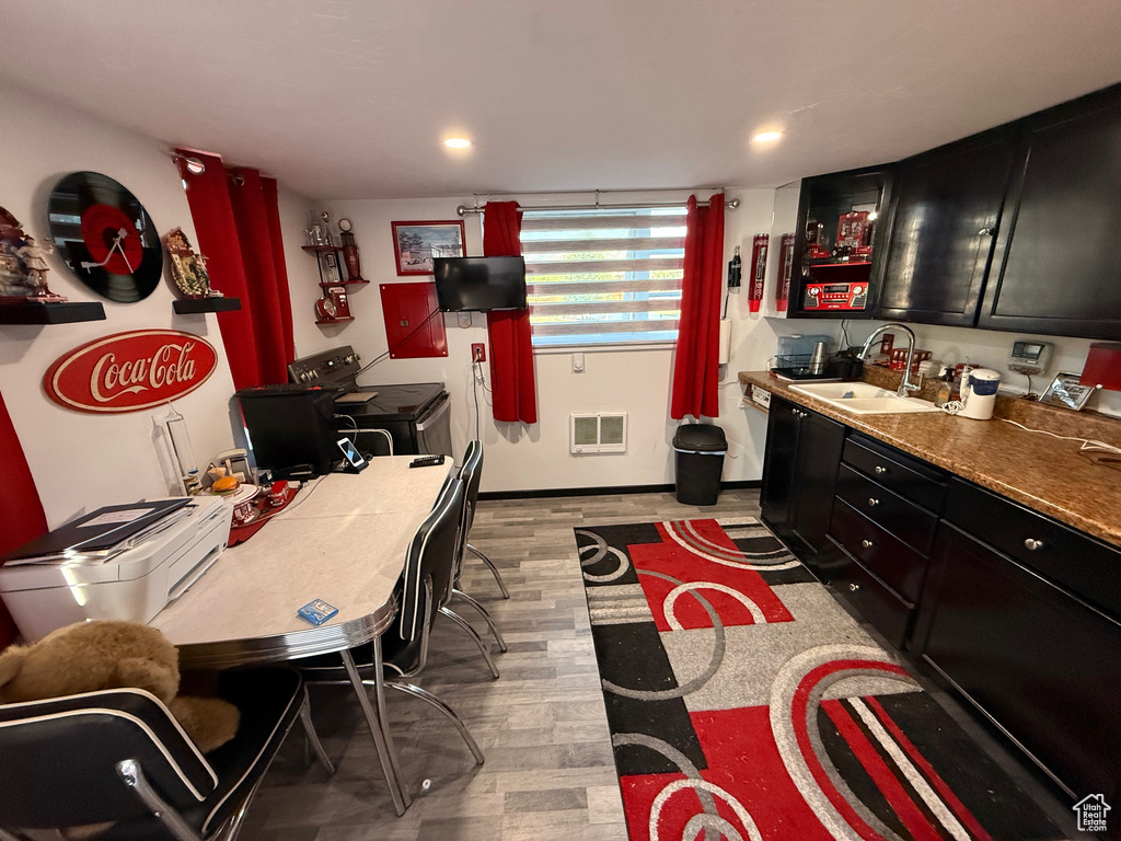 Kitchen with a sink, dark cabinets, light wood-type flooring, washer / clothes dryer, and recessed lighting