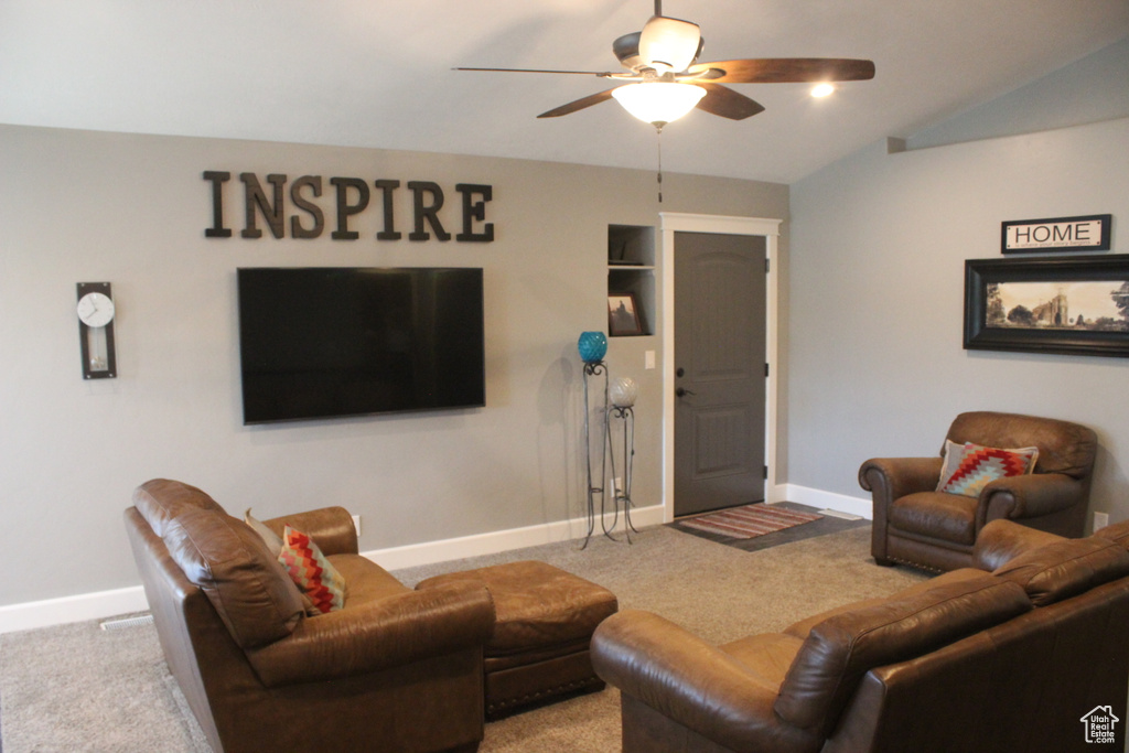 Carpeted living area featuring ceiling fan and baseboards