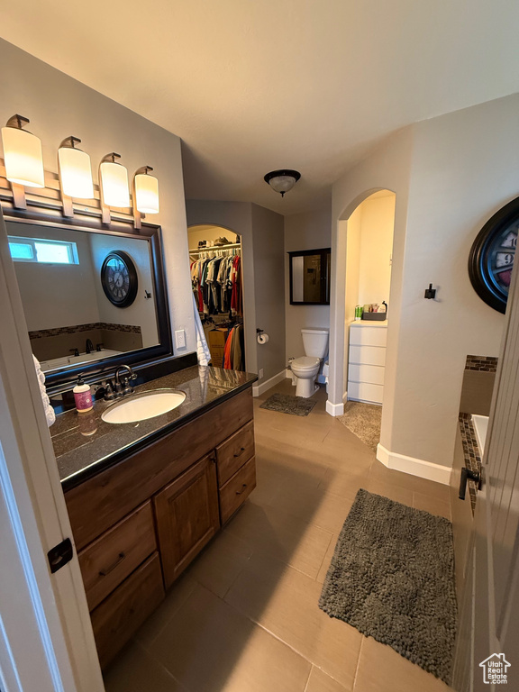 Bathroom featuring toilet, tile patterned flooring, vanity, a tub, and baseboards